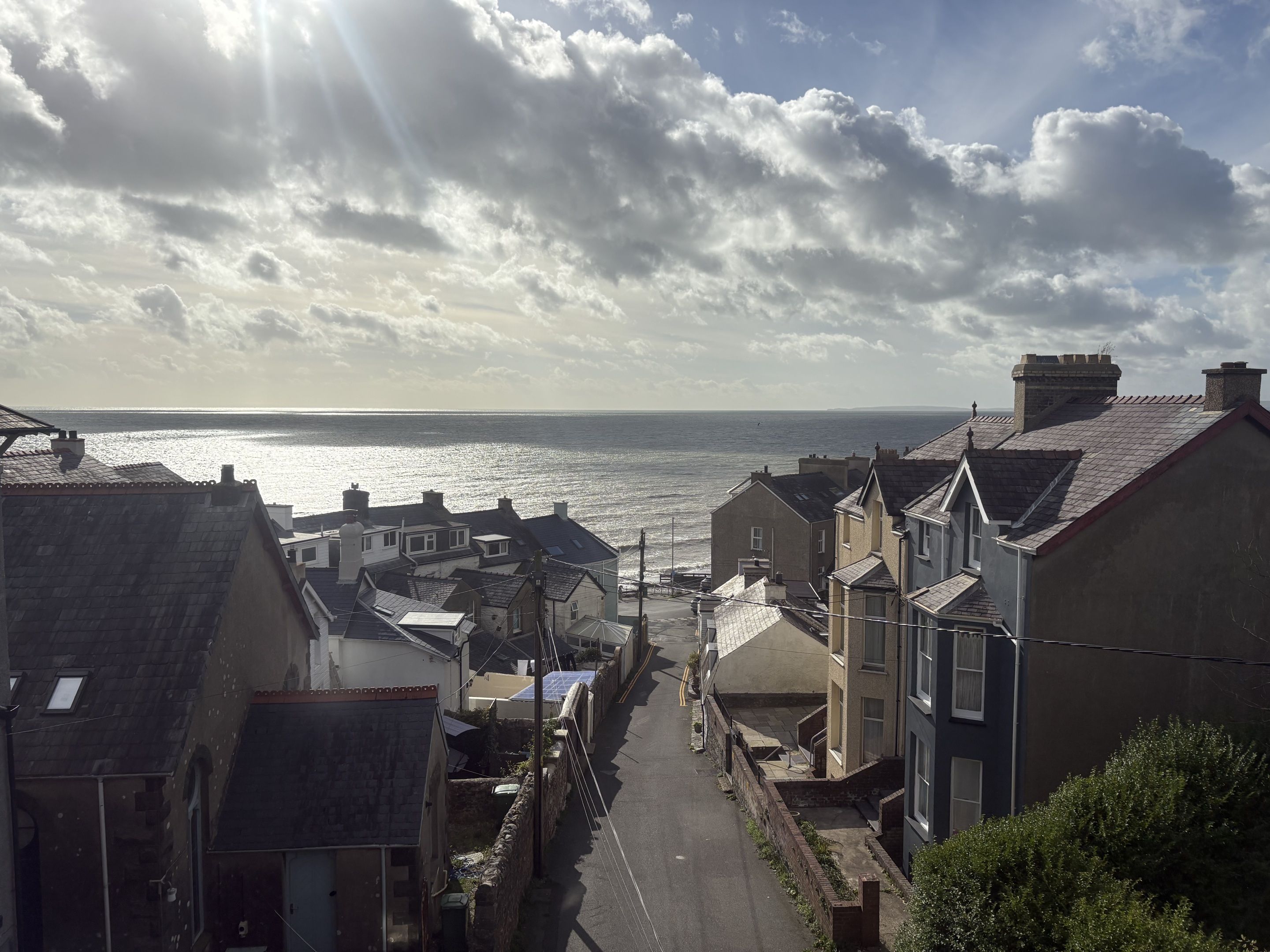 A coastal street with buildings, a clear sky, and the sea in the background.