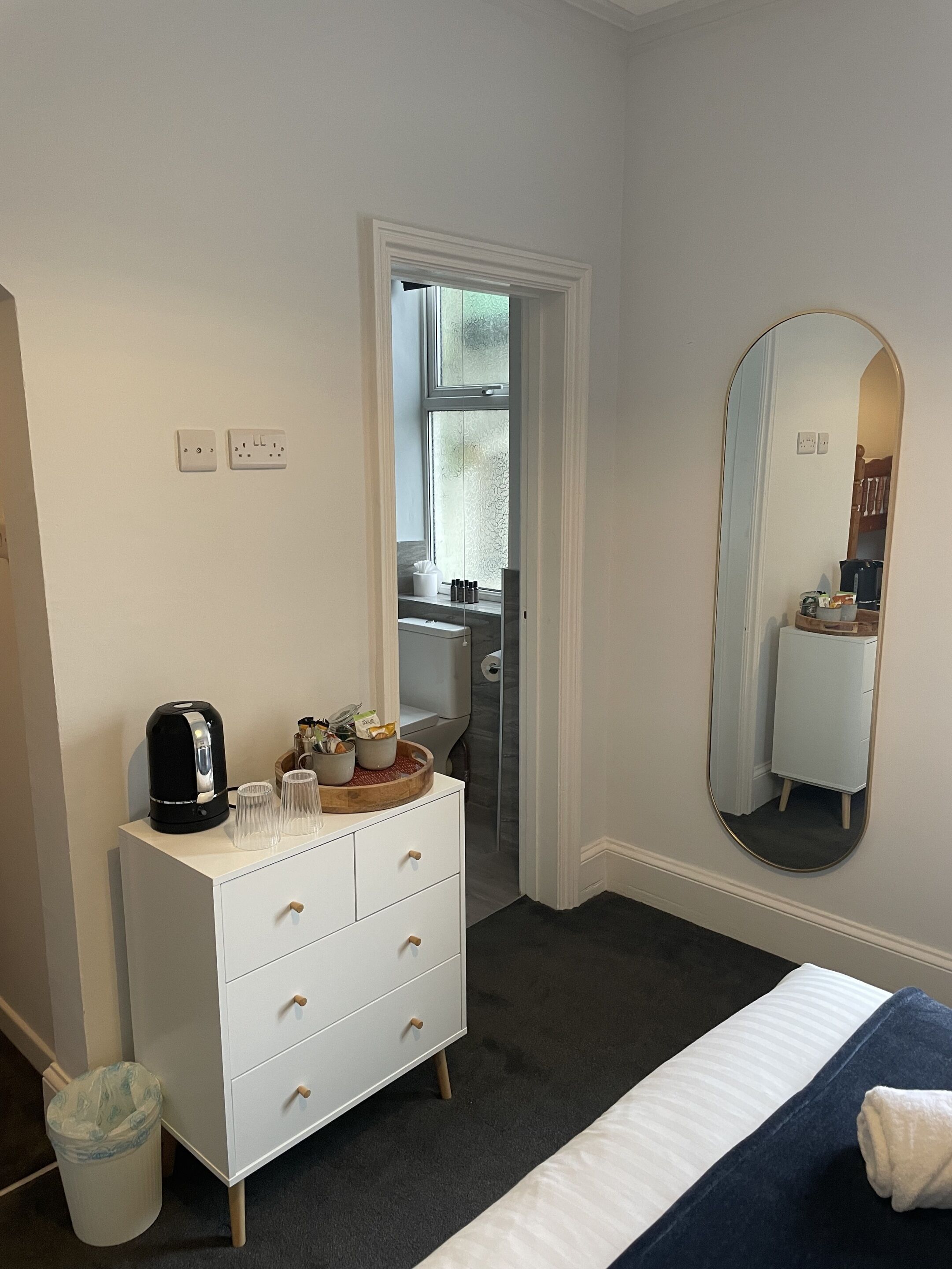 A bedroom with a bed, a dresser, a mirror, and a window.