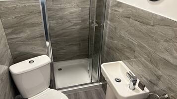A bathroom with a toilet, a shower with a glass door, and a sink with a mirror.