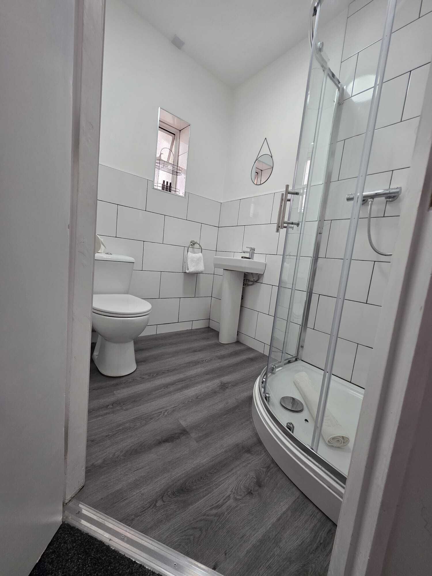 A bathroom with a toilet, sink, and glass shower enclosure.