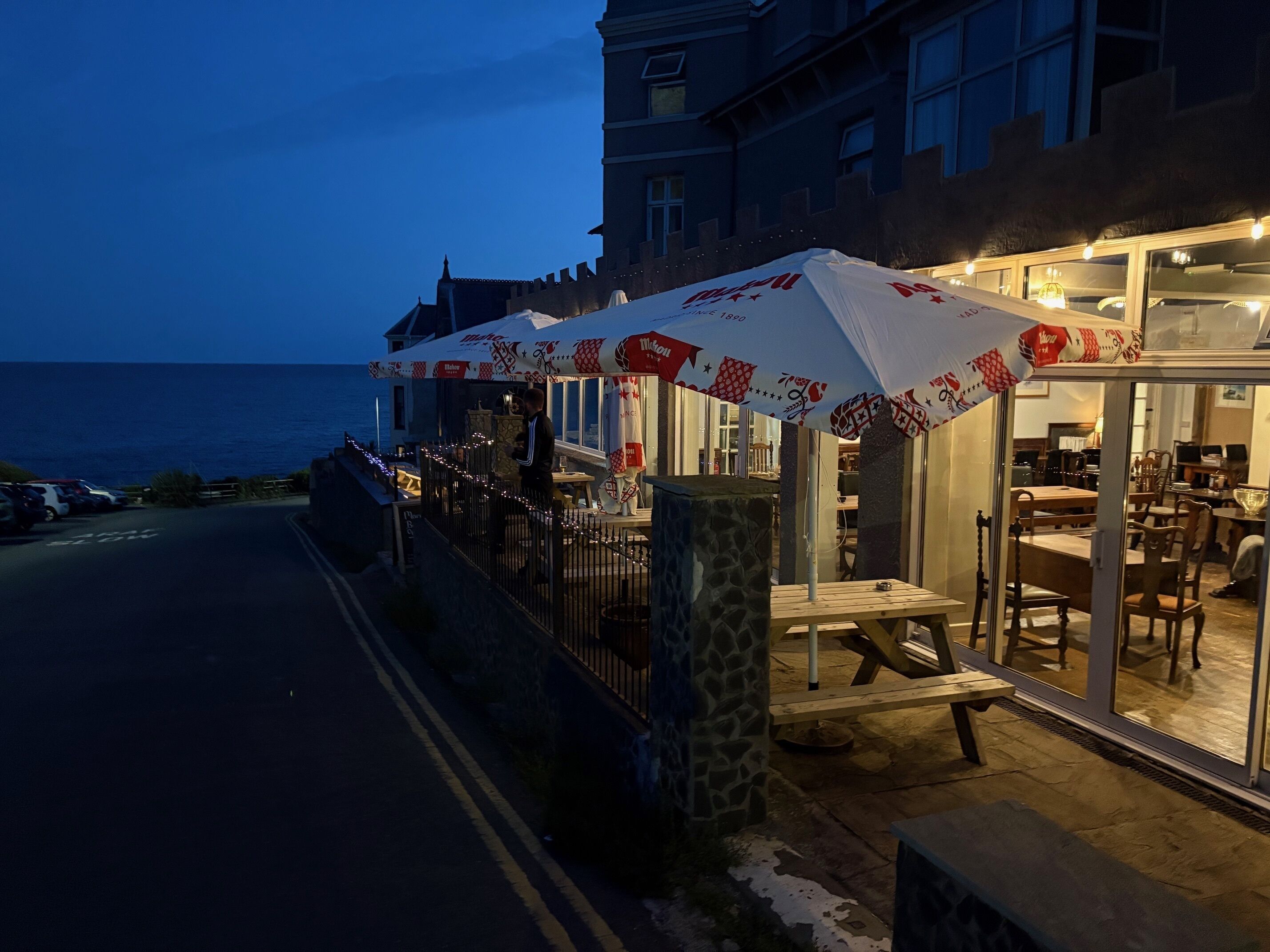 En restaurang vid havet med uteservering, en stenpelare och utsikt över havet.