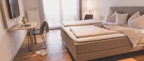 A hotel room with a bed, a desk, a chair, and a TV.