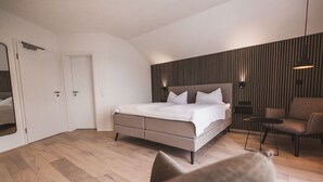 A modern bedroom with a large bed, a chair, and a small table. - Weingut Gehlen-Cornelius (Brauneberg)