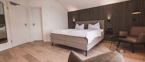 A modern bedroom with a large bed, a chair, and a small table.