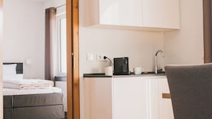 A modern hotel room with a bed, a small kitchen area with a coffee maker, and a dining table. - Weingut Gehlen-Cornelius (Brauneberg)