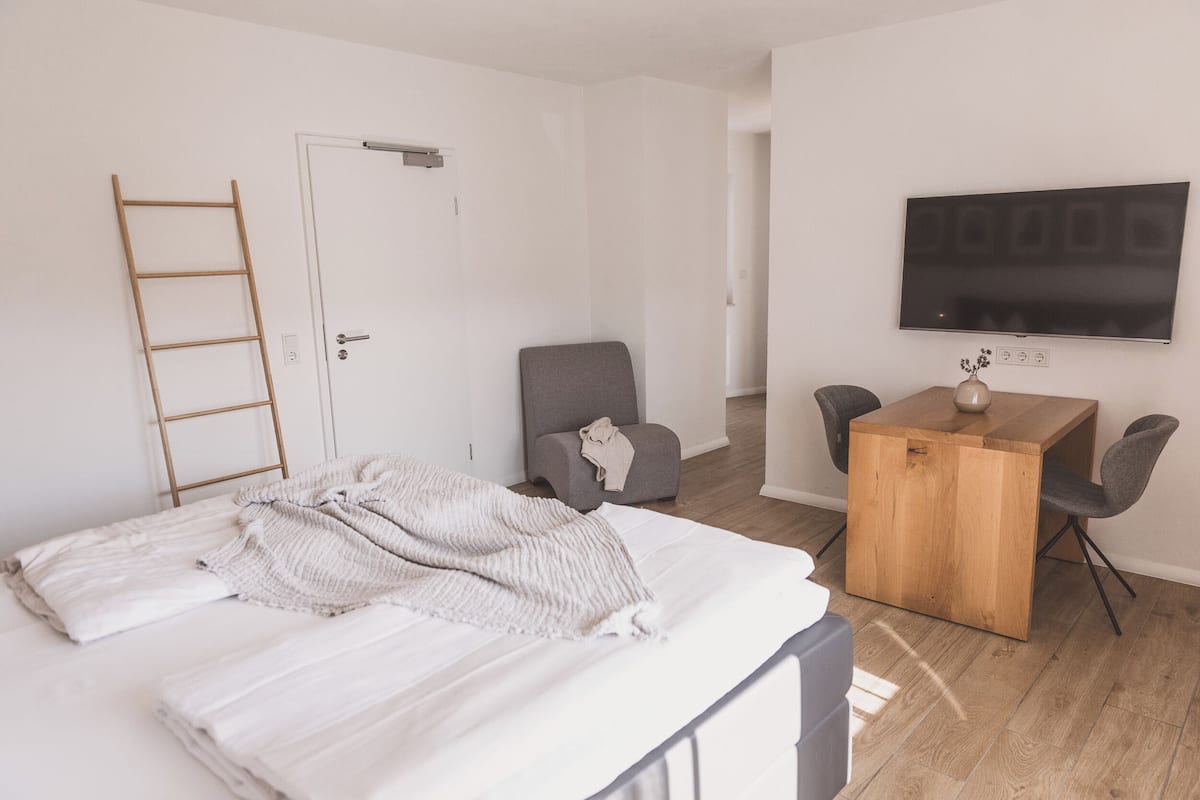 A minimalist bedroom with a bed, a desk, and a TV.