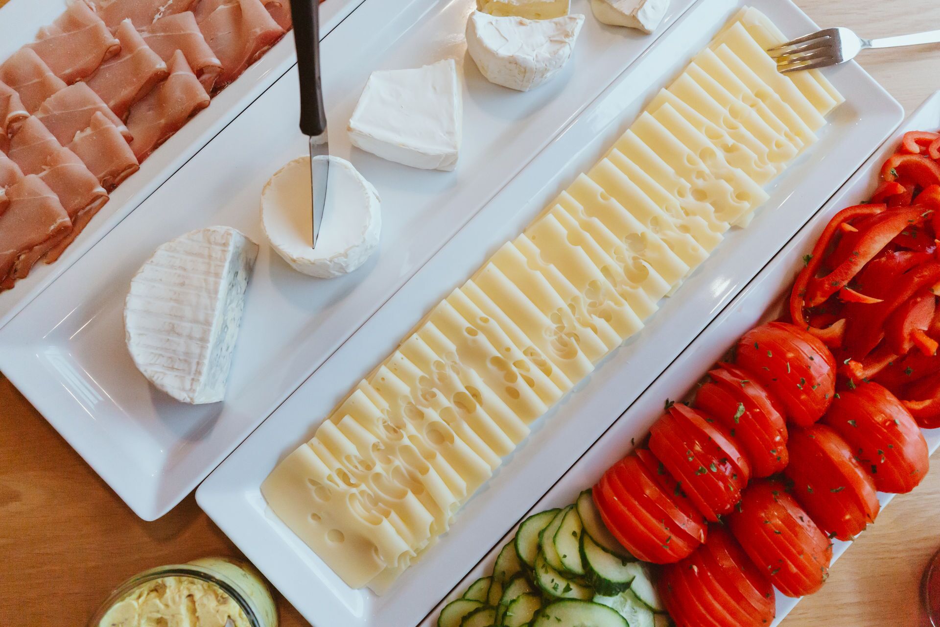Une assiette blanche contenant divers fromages, notamment une portion de brie, des tranches de camembert et un morceau de gouda.