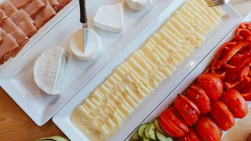 En vit tallrik med olika sorters ost, bland annat en hel Brie, skivor av Camembert och en bit Gouda.