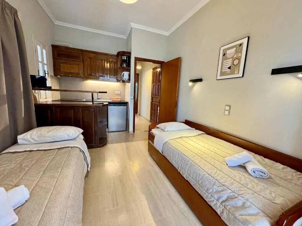Ein Hotelzimmer mit zwei Betten, einer Küchenzeile und einem Badezimmer.