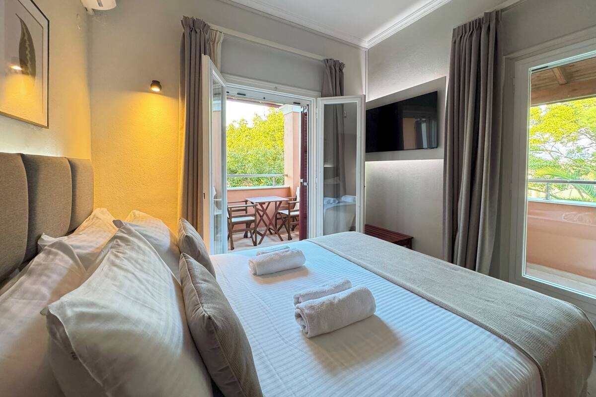 A hotel room with a bed, a desk, and a balcony.