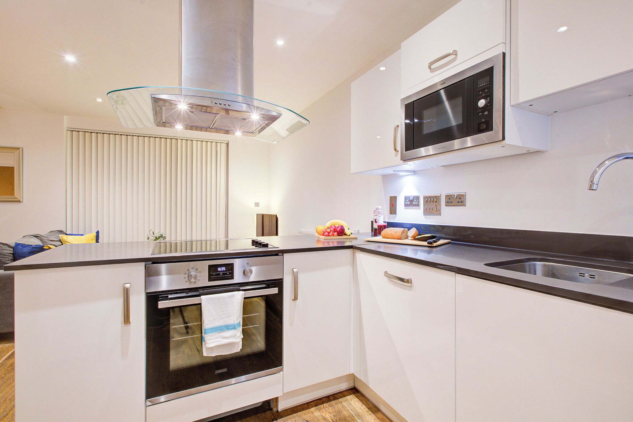 Een moderne keuken met roestvrijstalen apparatuur, een glazen afzuigkap en witte kastjes.