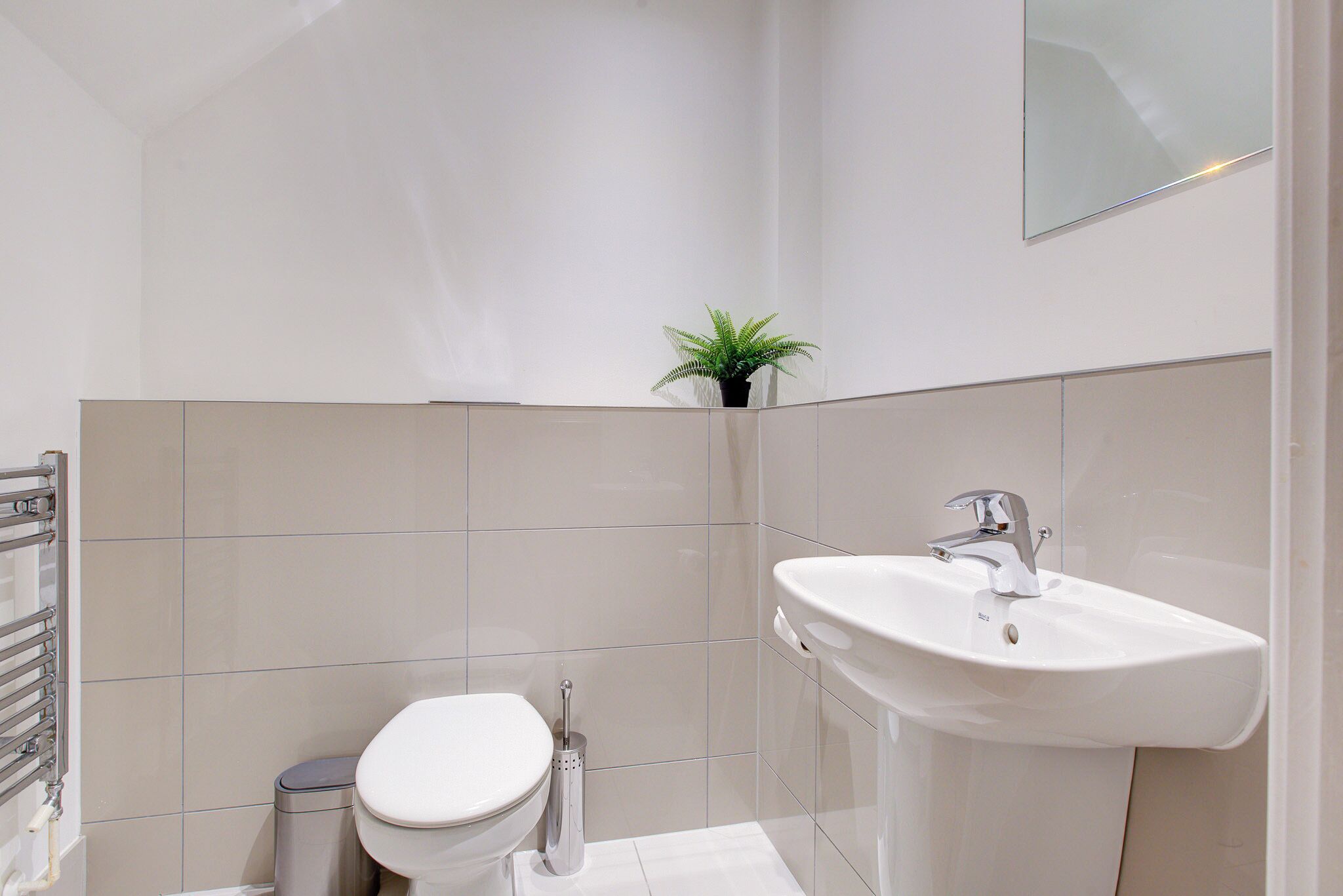 Ein modernes Badezimmer mit Toilette, Waschbecken und einem kleinen Topf mit Pflanze.