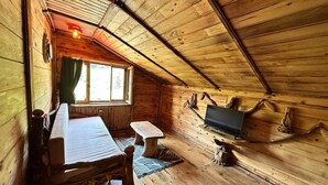 A cozy wooden cabin with a loft-style ceiling, a bed, a table, a bench, and a mounted television. - Rubaşi Butik Otel & Restoran (Findikli)
