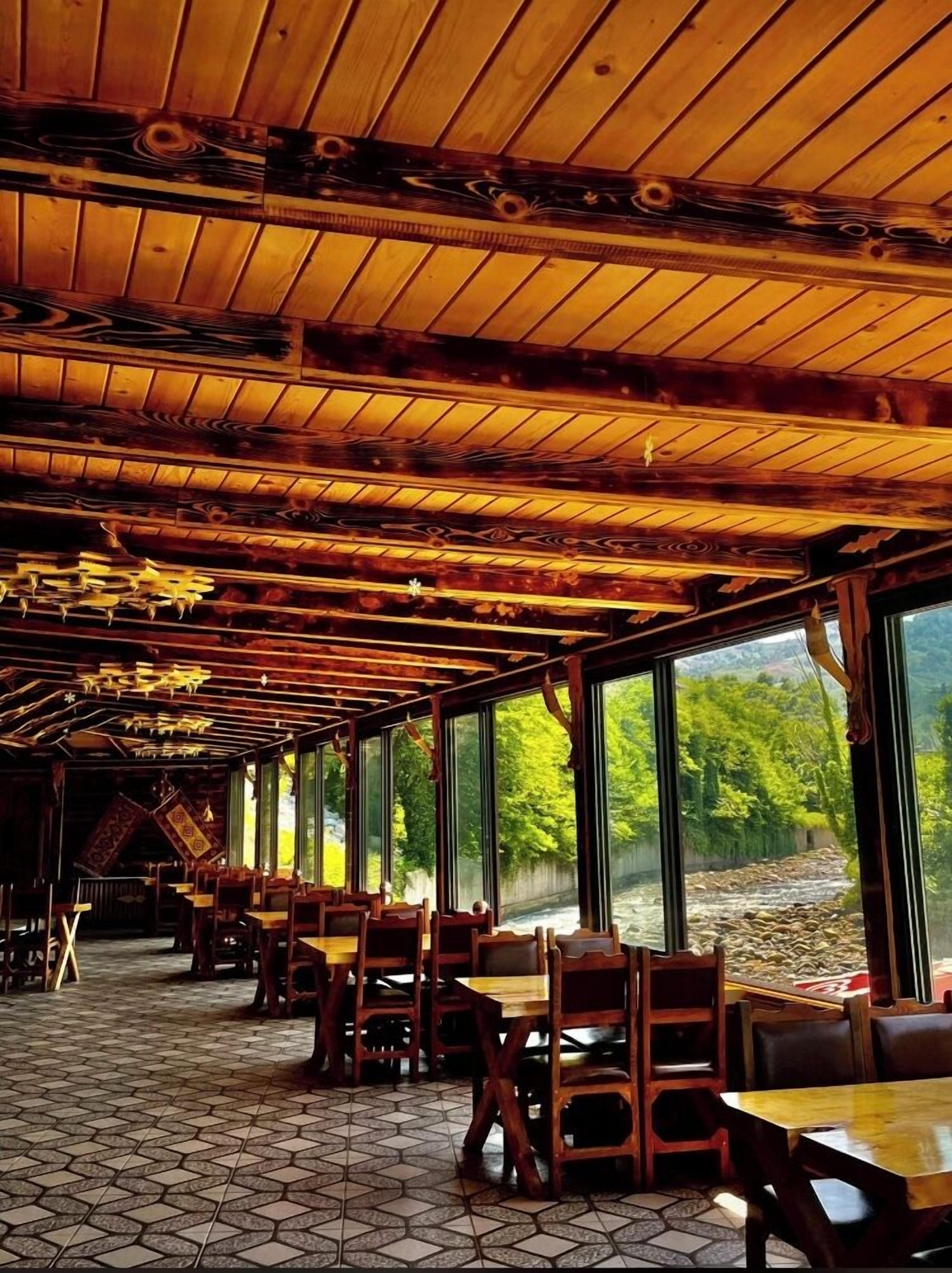 A restaurant with wooden ceiling beams, large windows, and tiled flooring. - Rubaşi Butik Otel & Restoran (Findikli)