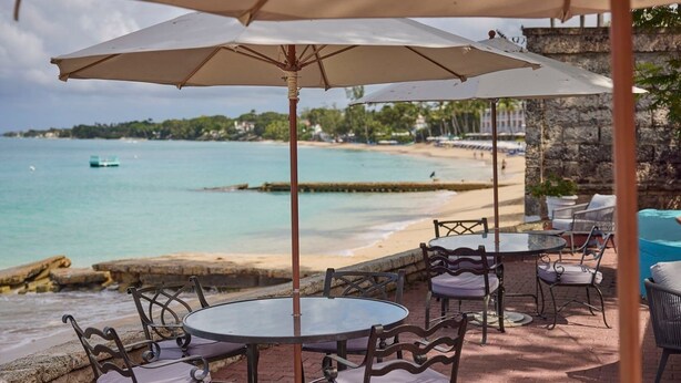 An outdoor seating area with tables and chairs, overlooking a beach and the sea. - Turtle View by Bluescape (Holetown)