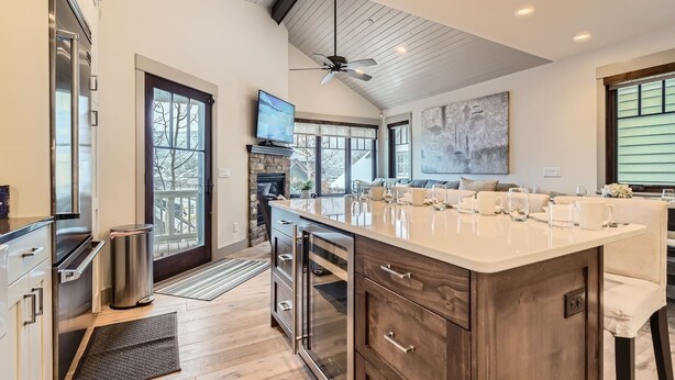 A modern kitchen with a large island, stainless steel appliances, and a fireplace. - 916 Empire Skiers Secret 4 Bedroom Home (Park City)