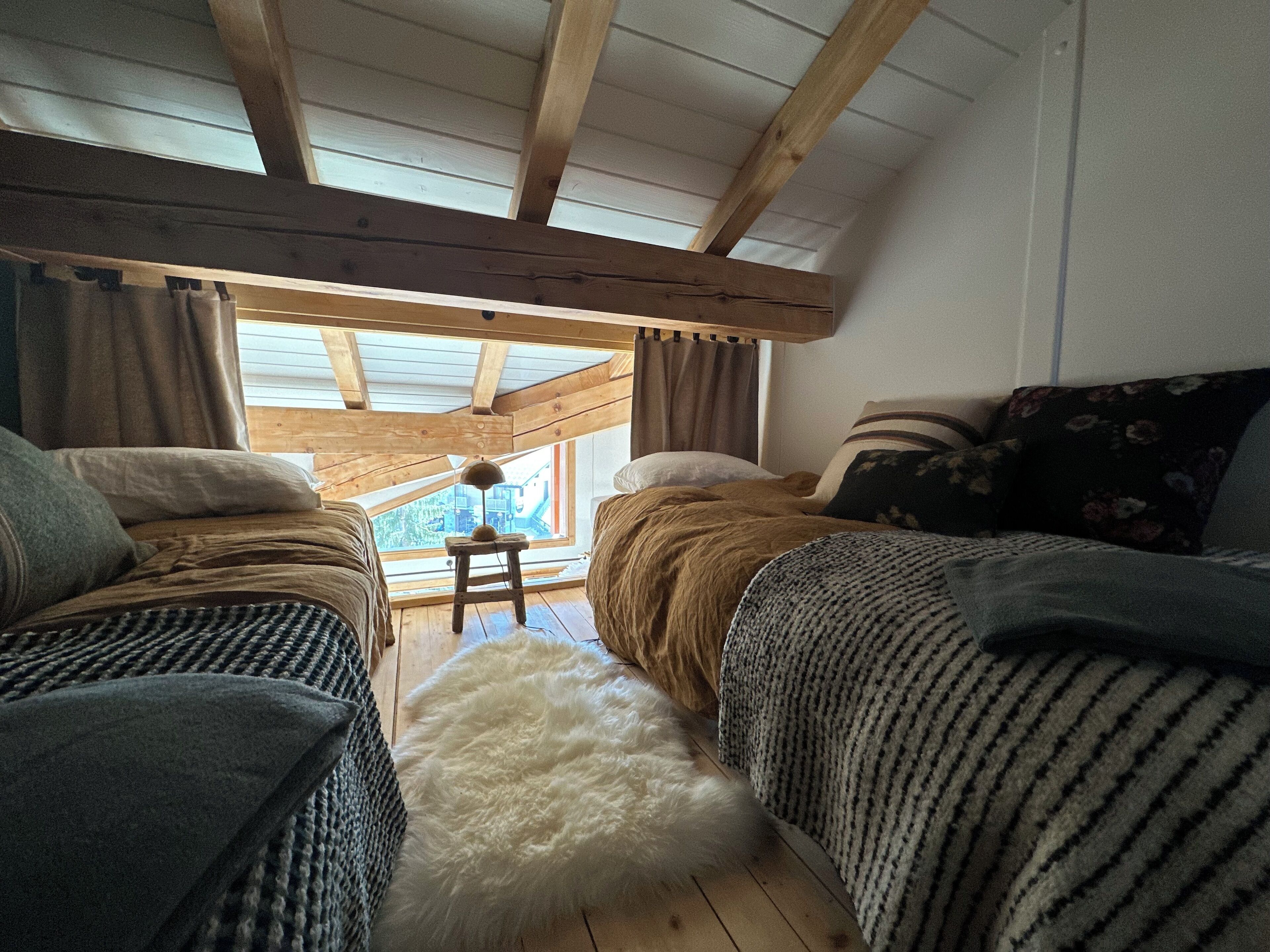 Een gezellig slaapkamer met twee bedden, een zacht vloerkleed en uitzicht op de omgeving door een raam.