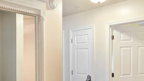 Un pasillo con suelo de madera, puertas blancas y un espejo con marco decorativo.