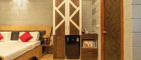 Une chambre avec un lit, une armoire, un petit réfrigérateur et une porte.