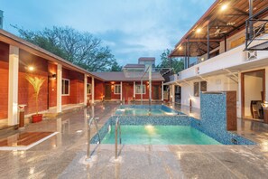 A swimming pool with a tiled edge, surrounded by a covered area with a roof and railings. - Seasons Suites HBR (Bengaluru)
