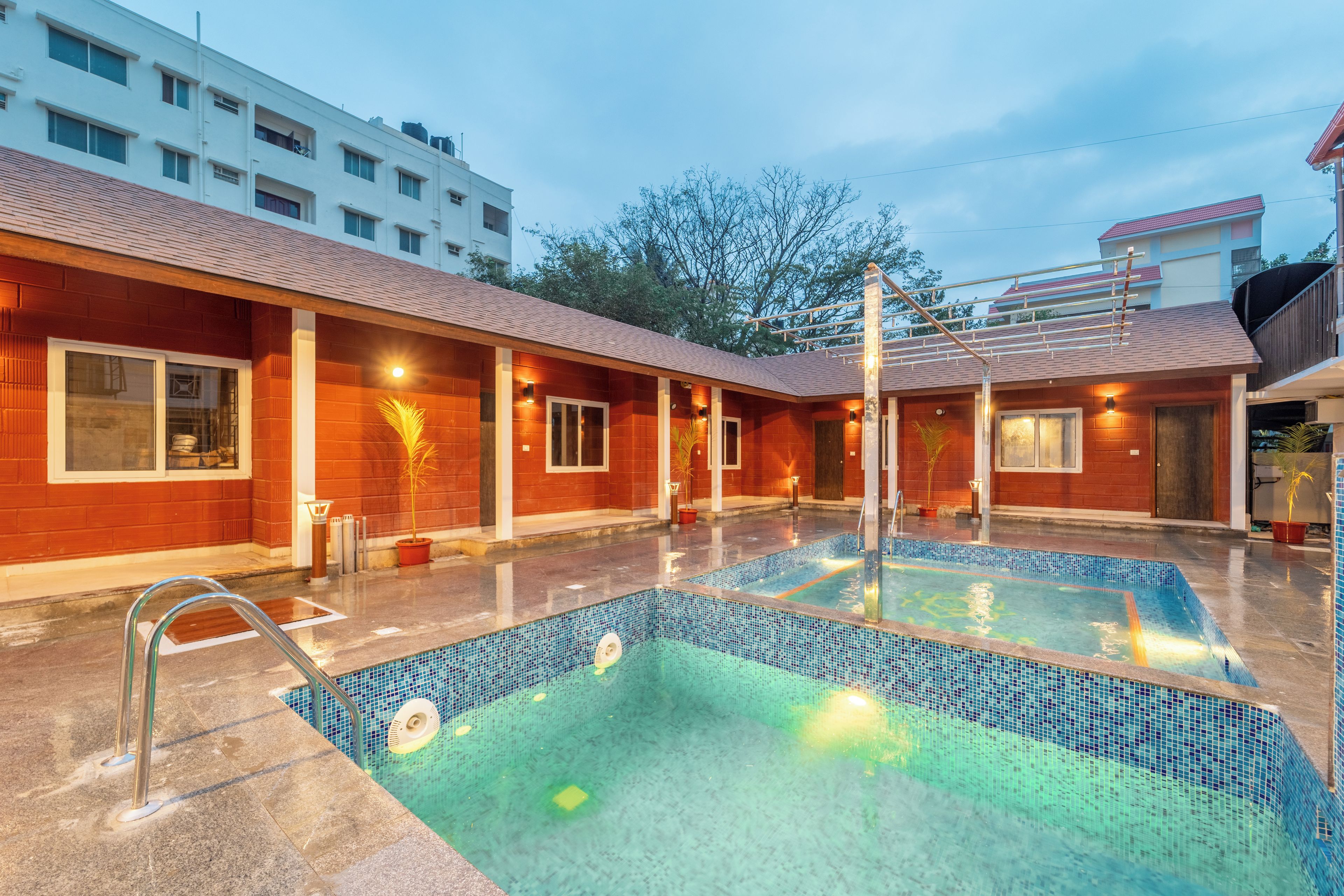 A swimming pool with a tiled edge, surrounded by a building with a red brick facade and multiple windows.