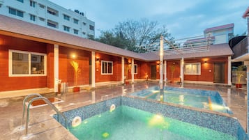 A swimming pool with a tiled edge, surrounded by a building with a red brick facade and multiple windows.