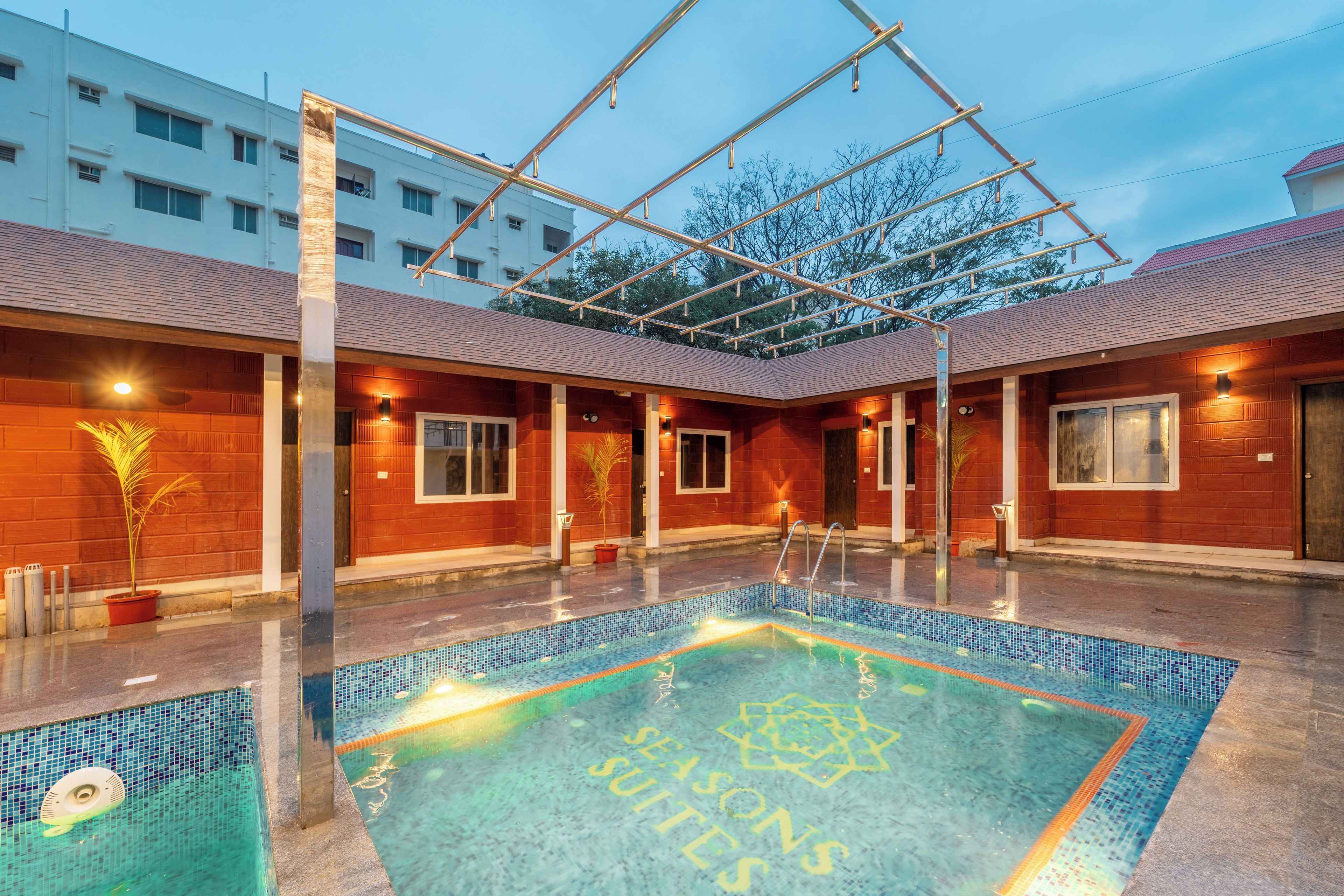 Una piscina con un diseño geométrico en el piso, rodeada por una zona techada con estructura metálica.