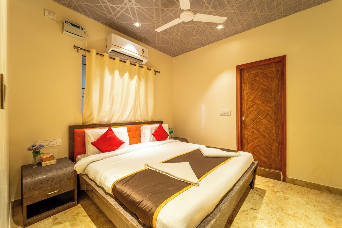 A hotel room with a bed, a nightstand, a wooden door, and a ceiling fan.