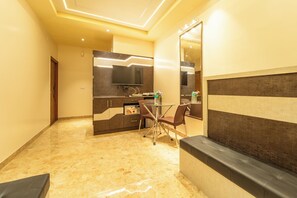 A hotel room with a dining area, a sofa, and a large mirror. - Seasons Suites HBR (Bengaluru)
