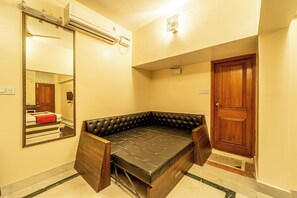 A room with a built-in sofa bed, a mirror, an air conditioning unit, and a wooden door. - Seasons Suites HBR (Bengaluru)