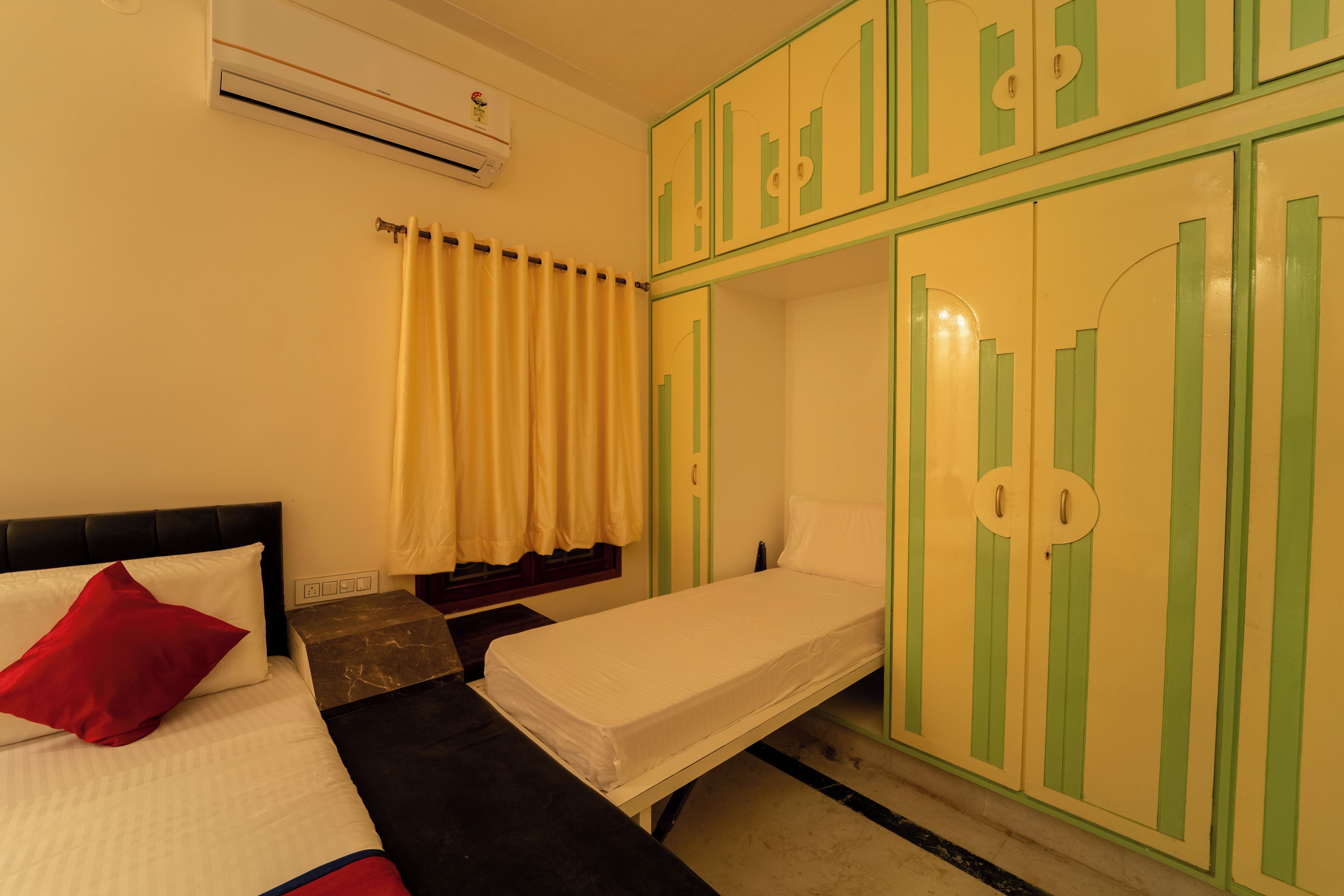 Ein Hotelzimmer mit Bett, einem kleinen Tisch, einem Kleiderschrank und einer Klimaanlage.