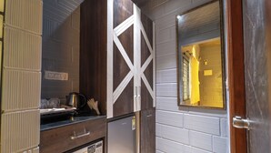 A compact kitchen with a built-in refrigerator, a microwave, and a coffee maker on the counter. - Seasons Suites HBR (Bengaluru)
