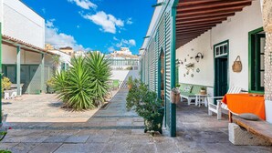 Une rue étroite, avec un bâtiment sur le côté droit, caractérisé par un balcon en bois et une porte verte.