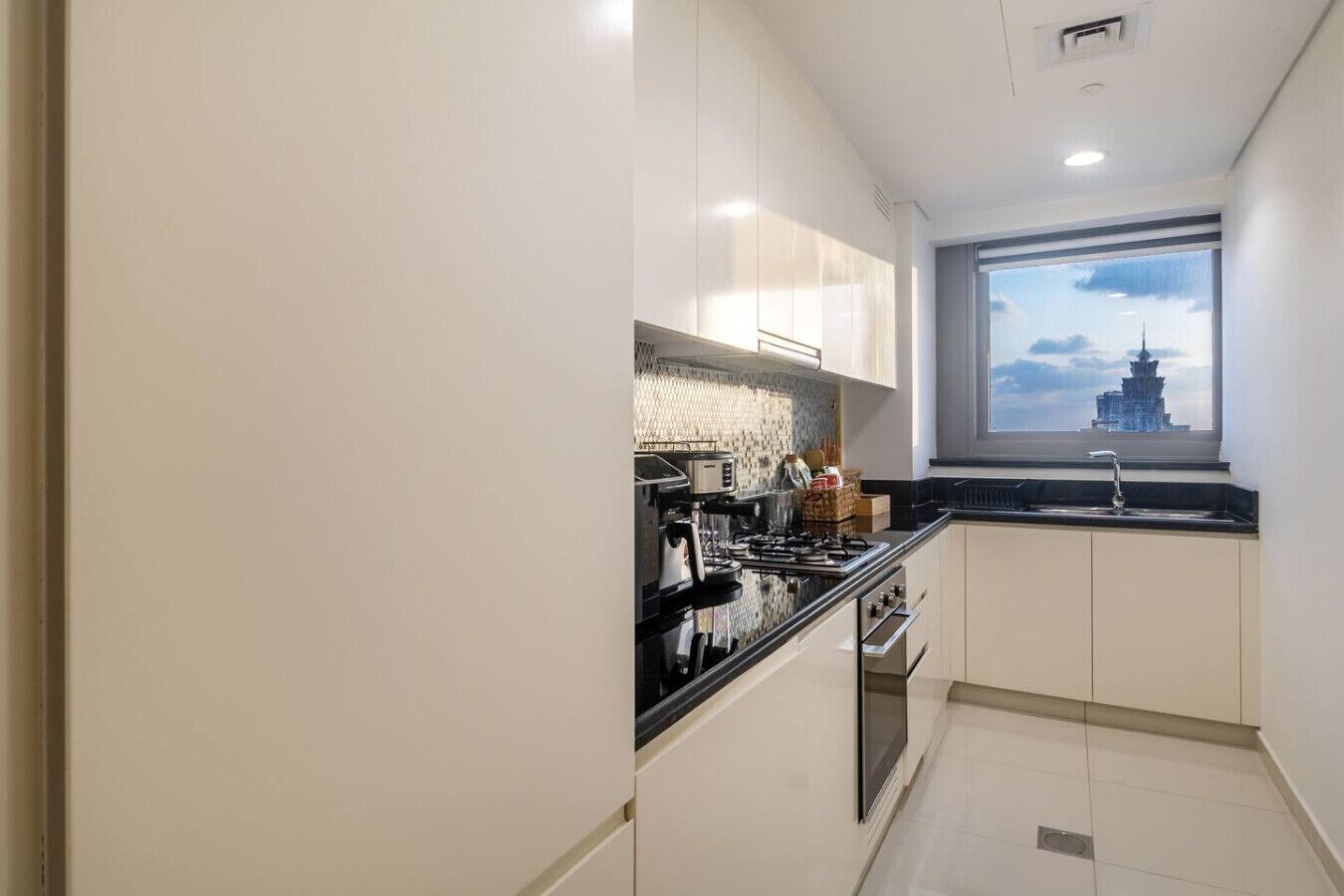 A compact kitchen with a gas stove, a sink, and a window with a view of a pagoda.