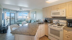 A kitchen with a granite countertop, white cabinets, a stove, and a microwave. - Elegance & Comfort | Coastal Retreat (St. Pete Beach)