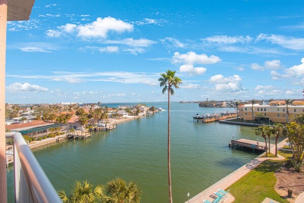 A waterfront view with a marina, palm trees, and buildings along the shore.
