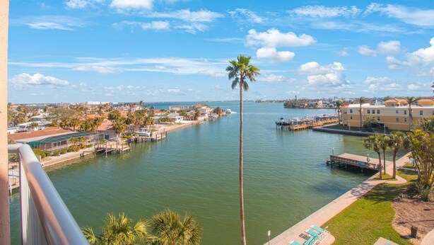 A waterfront view with a marina, palm trees, and buildings along the shore. - Elegance & Comfort | Coastal Retreat (St. Pete Beach)