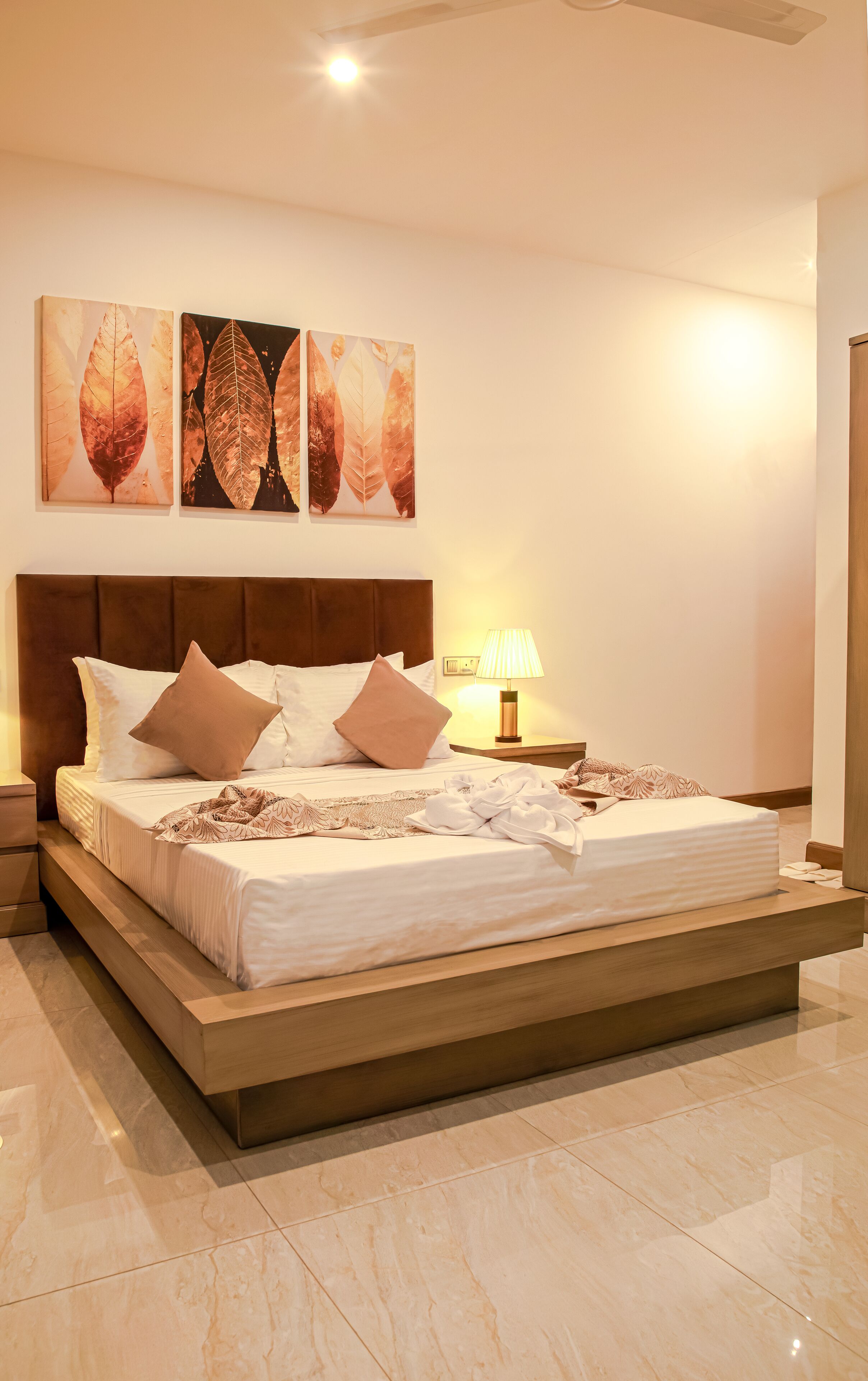 A modern hotel bedroom with a large bed, a nightstand, and wall art.