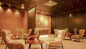 A modern lounge area with leather armchairs, round tables, and potted plants. - Ravo Hotel (Galle)
