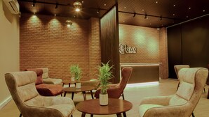 A hotel lobby with brick walls, a reception desk, and seating areas with chairs and tables. - Ravo Hotel (Galle)