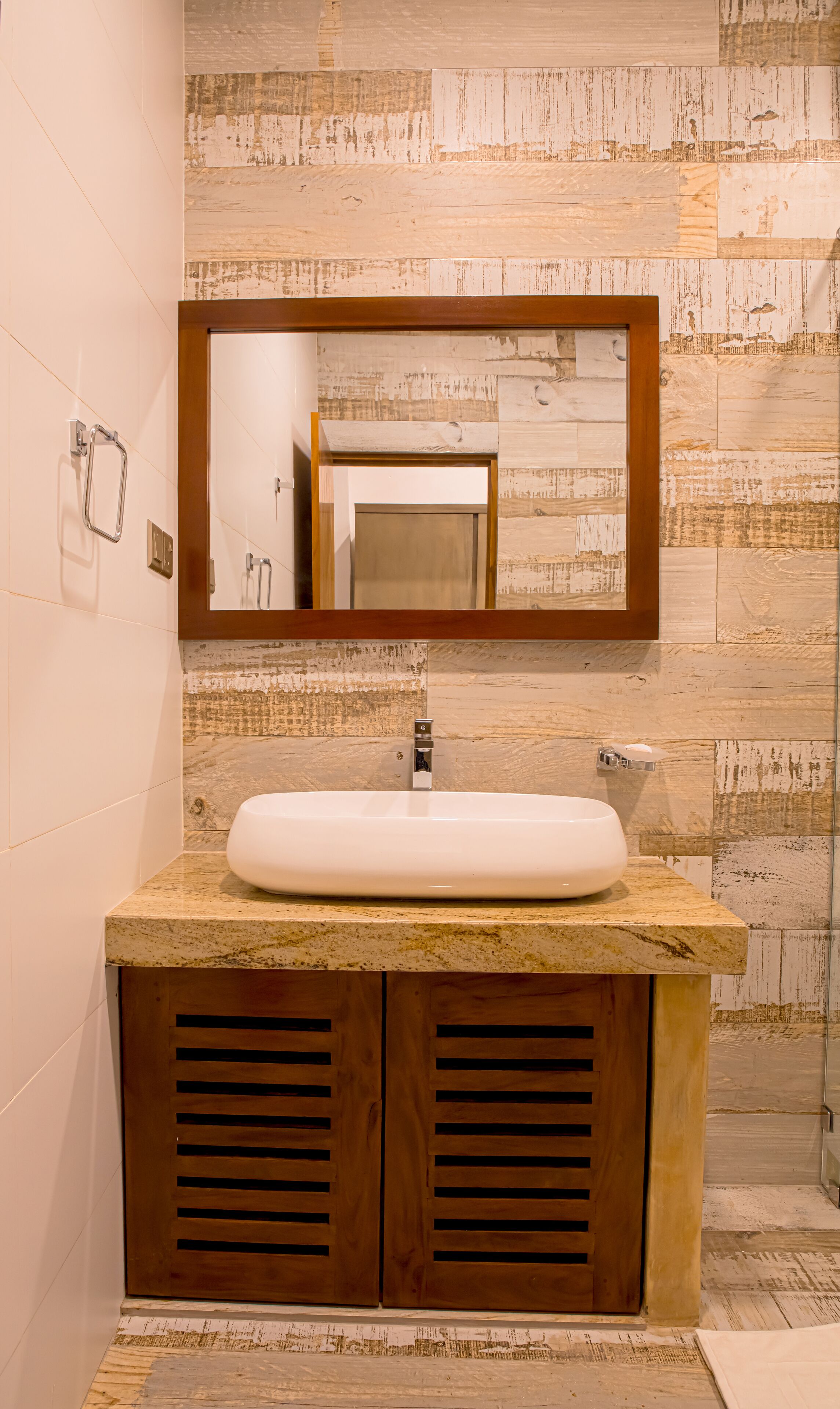 A bathroom with a wooden vanity, a white sink, and a mirror above it.