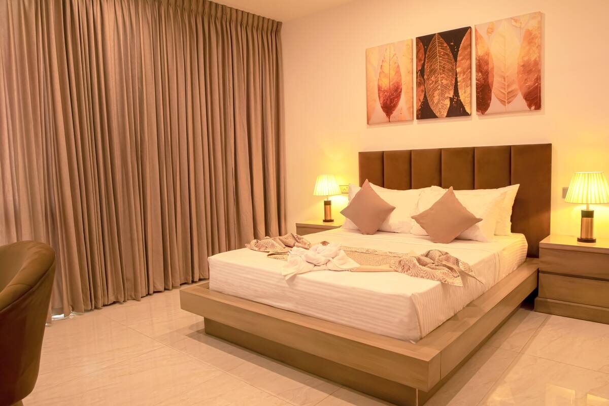 A neatly made bed with pillows, a headboard, and bedside lamps.
