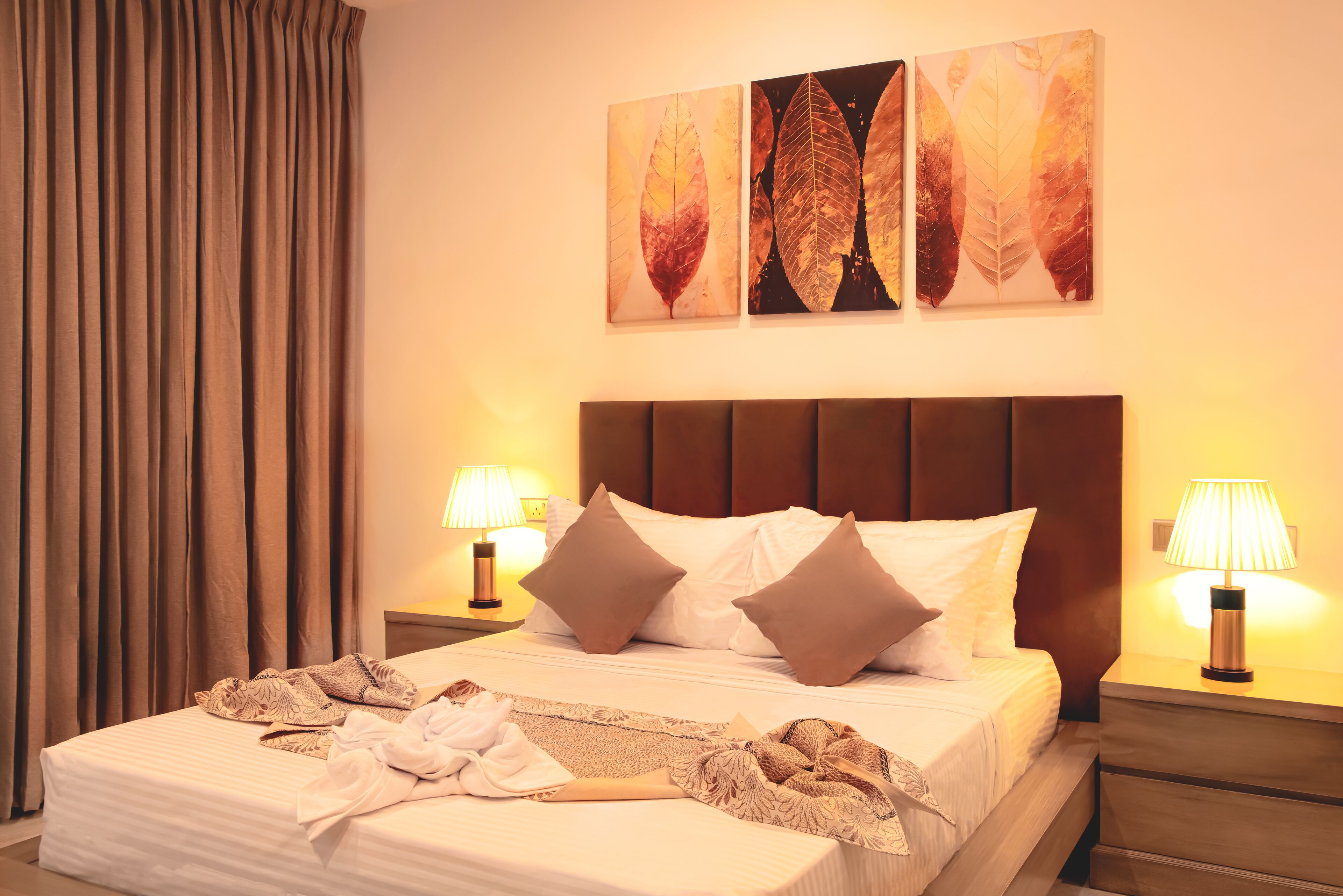 A neatly made bed with pillows, a bedside lamp, and a blanket.