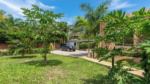 A residential property with a paved driveway, a parked SUV, and lush greenery including palm trees and various plants. - Babylon Gardens (Diani Beach)