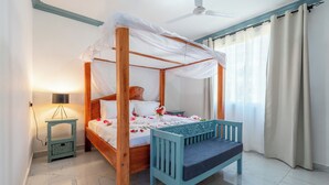 A four-poster bed with a canopy, a bedside table with a lamp, and a bench beside the bed. - Babylon Gardens (Diani Beach)