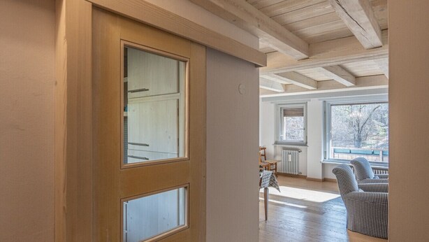 A hallway with a wooden door, a radiator, and a view into a living area with a table and chairs. - Casa Funivia, Casa Funivia, close to the center and the cableway (Cortina d´Ampezzo)