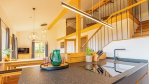 A modern kitchen with a granite countertop, wooden beams, and a built-in sink.
