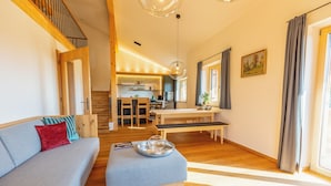 A modern living room with a sofa, ottoman, and dining area.