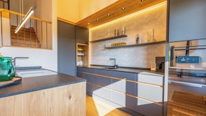 A modern kitchen with wooden accents, built-in shelves, and a sleek countertop.