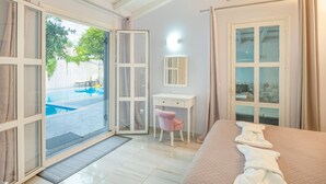 Quarto de hotel com cama, escrivaninha, cadeira e vista para a piscina.